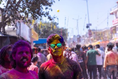 Barsana, Uttar Pradesh, India - March 18 2024: Group of hindu devotee with color of their faces celebrating the festival of holi on the streets of barsana with dry organic colours. clipart