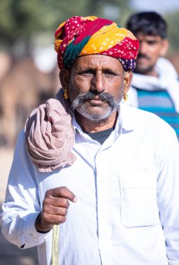 Bikaner, Rajasthan, Hindistan - 14 Ocak 2023: Bikaner deve festivali sırasında kum tepelerinde geleneksel giyinmiş bir rajasthani erkeğinin portresi.