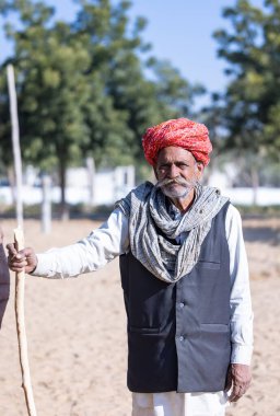 Bikaner, Rajasthan, Hindistan - 14 Ocak 2023: Bikaner deve festivali sırasında kum tepelerinde geleneksel giyinmiş bir rajasthani erkeğinin portresi.