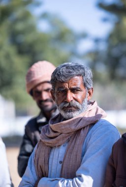 Bikaner, Rajasthan, Hindistan - 14 Ocak 2023: Bikaner deve festivali sırasında kum tepelerinde geleneksel giyinmiş bir rajasthani erkeğinin portresi.