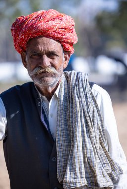 Bikaner, Rajasthan, Hindistan - 14 Ocak 2023: Bikaner deve festivali sırasında kum tepelerinde geleneksel giyinmiş bir rajasthani erkeğinin portresi.