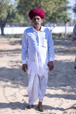 Bikaner, Rajasthan, Hindistan - 14 Ocak 2023: Bikaner deve festivali sırasında kum tepelerinde geleneksel giyinmiş bir rajasthani erkeğinin portresi.