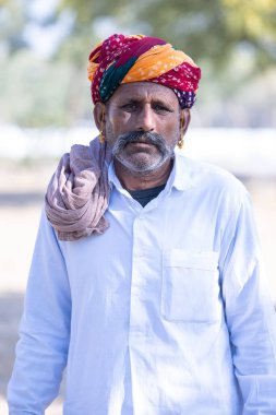Bikaner, Rajasthan, Hindistan - 14 Ocak 2023: Bikaner deve festivali sırasında kum tepelerinde geleneksel giyinmiş bir rajasthani erkeğinin portresi.