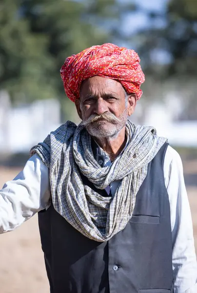 Bikaner, Rajasthan, Hindistan - 14 Ocak 2023: Bikaner deve festivali sırasında kum tepelerinde geleneksel giyinmiş bir rajasthani erkeğinin portresi.