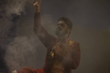 Varanasi, Uttar Pradesh, Hindistan - 20 Ocak 2024: Ganga aarti, genç bir Hindu papazın portresi sabahın erken saatlerinde Assi Ghat 'ta geleneksel ayinlerle geleneksel kıyafetlerle Ganga nehri aarti sergiliyor..