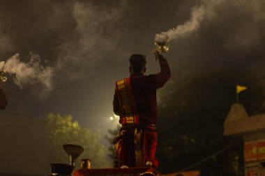 Varanasi, Uttar Pradesh, Hindistan - 20 Ocak 2024: Ganga aarti, genç bir Hindu papazın portresi sabahın erken saatlerinde Assi Ghat 'ta geleneksel ayinlerle geleneksel kıyafetlerle Ganga nehri aarti sergiliyor..
