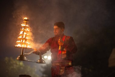 Varanasi, Uttar Pradesh, Hindistan - 20 Ocak 2024: Ganga aarti, genç bir Hindu papazın portresi sabahın erken saatlerinde Assi Ghat 'ta geleneksel ayinlerle geleneksel kıyafetlerle Ganga nehri aarti sergiliyor..