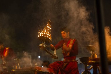 Varanasi, Uttar Pradesh, Hindistan - 20 Ocak 2024: Ganga aarti, genç bir Hindu papazın portresi sabahın erken saatlerinde Assi Ghat 'ta geleneksel ayinlerle geleneksel kıyafetlerle Ganga nehri aarti sergiliyor..