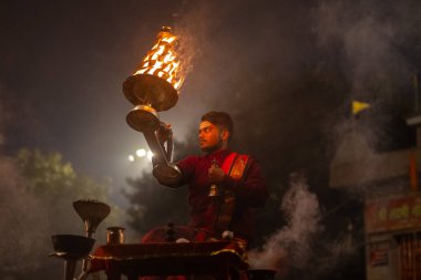 Varanasi, Uttar Pradesh, Hindistan - 20 Ocak 2024: Ganga aarti, genç bir Hindu papazın portresi sabahın erken saatlerinde Assi Ghat 'ta geleneksel ayinlerle geleneksel kıyafetlerle Ganga nehri aarti sergiliyor..