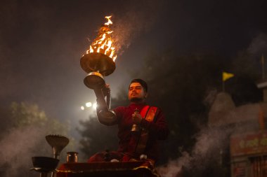 Varanasi, Uttar Pradesh, Hindistan - 20 Ocak 2024: Ganga aarti, genç bir Hindu papazın portresi sabahın erken saatlerinde Assi Ghat 'ta geleneksel ayinlerle geleneksel kıyafetlerle Ganga nehri aarti sergiliyor..