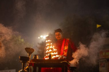 Varanasi, Uttar Pradesh, Hindistan - 20 Ocak 2024: Ganga aarti, genç bir Hindu papazın portresi sabahın erken saatlerinde Assi Ghat 'ta geleneksel ayinlerle geleneksel kıyafetlerle Ganga nehri aarti sergiliyor..