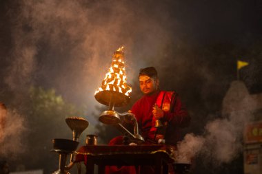 Varanasi, Uttar Pradesh, Hindistan - 20 Ocak 2024: Ganga aarti, genç bir Hindu papazın portresi sabahın erken saatlerinde Assi Ghat 'ta geleneksel ayinlerle geleneksel kıyafetlerle Ganga nehri aarti sergiliyor..