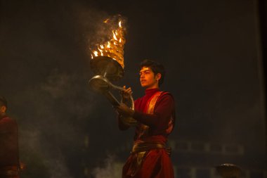 Varanasi, Uttar Pradesh, Hindistan - 20 Ocak 2024: Ganga aarti, genç bir Hindu papazın portresi sabahın erken saatlerinde Assi Ghat 'ta geleneksel ayinlerle geleneksel kıyafetlerle Ganga nehri aarti sergiliyor..