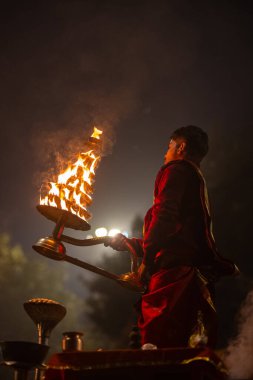 Varanasi, Uttar Pradesh, Hindistan - 20 Ocak 2024: Ganga aarti, genç bir Hindu papazın portresi sabahın erken saatlerinde Assi Ghat 'ta geleneksel ayinlerle geleneksel kıyafetlerle Ganga nehri aarti sergiliyor..