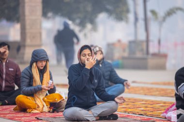 Varanasi, Uttar Pradesh, Hindistan - 20 Ocak 2024: Ganga aarti, genç bir Hindu papazın portresi sabahın erken saatlerinde Assi Ghat 'ta geleneksel ayinlerle geleneksel kıyafetlerle Ganga nehri aarti sergiliyor..
