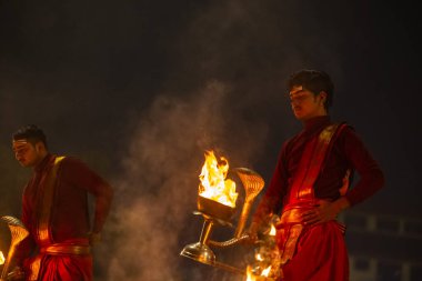 Varanasi, Uttar Pradesh, Hindistan - 20 Ocak 2024: Ganga aarti, genç bir Hindu papazın portresi sabahın erken saatlerinde Assi Ghat 'ta geleneksel ayinlerle geleneksel kıyafetlerle Ganga nehri aarti sergiliyor..