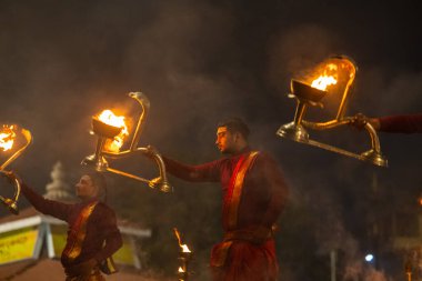 Varanasi, Uttar Pradesh, Hindistan - 20 Ocak 2024: Ganga aarti, genç bir Hindu papazın portresi sabahın erken saatlerinde Assi Ghat 'ta geleneksel ayinlerle geleneksel kıyafetlerle Ganga nehri aarti sergiliyor..