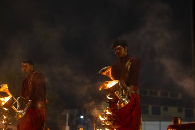 Varanasi, Uttar Pradesh, Hindistan - 20 Ocak 2024: Ganga aarti, genç bir Hindu papazın portresi sabahın erken saatlerinde Assi Ghat 'ta geleneksel ayinlerle geleneksel kıyafetlerle Ganga nehri aarti sergiliyor..