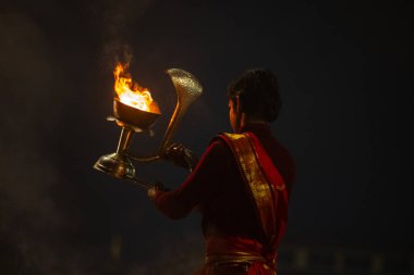 Varanasi, Uttar Pradesh, Hindistan - 20 Ocak 2024: Ganga aarti, genç bir Hindu papazın portresi sabahın erken saatlerinde Assi Ghat 'ta geleneksel ayinlerle geleneksel kıyafetlerle Ganga nehri aarti sergiliyor..