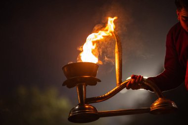 Varanasi, Uttar Pradesh, Hindistan - 20 Ocak 2024: Ganga aarti, genç bir Hindu papazın portresi sabahın erken saatlerinde Assi Ghat 'ta geleneksel ayinlerle geleneksel kıyafetlerle Ganga nehri aarti sergiliyor..