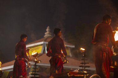Varanasi, Uttar Pradesh, Hindistan - 20 Ocak 2024: Ganga aarti, genç bir Hindu papazın portresi sabahın erken saatlerinde Assi Ghat 'ta geleneksel ayinlerle geleneksel kıyafetlerle Ganga nehri aarti sergiliyor..