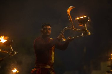 Varanasi, Uttar Pradesh, Hindistan - 20 Ocak 2024: Ganga aarti, genç bir Hindu papazın portresi sabahın erken saatlerinde Assi Ghat 'ta geleneksel ayinlerle geleneksel kıyafetlerle Ganga nehri aarti sergiliyor..