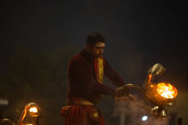 Varanasi, Uttar Pradesh, Hindistan - 20 Ocak 2024: Ganga aarti, genç bir Hindu papazın portresi sabahın erken saatlerinde Assi Ghat 'ta geleneksel ayinlerle geleneksel kıyafetlerle Ganga nehri aarti sergiliyor..