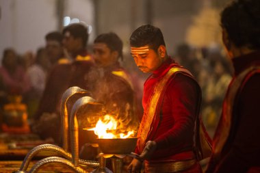 Varanasi, Uttar Pradesh, Hindistan - 20 Ocak 2024: Ganga aarti, genç bir Hindu papazın portresi sabahın erken saatlerinde Assi Ghat 'ta geleneksel ayinlerle geleneksel kıyafetlerle Ganga nehri aarti sergiliyor..