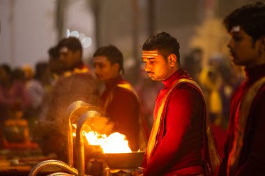 Varanasi, Uttar Pradesh, Hindistan - 20 Ocak 2024: Ganga aarti, genç bir Hindu papazın portresi sabahın erken saatlerinde Assi Ghat 'ta geleneksel ayinlerle geleneksel kıyafetlerle Ganga nehri aarti sergiliyor..