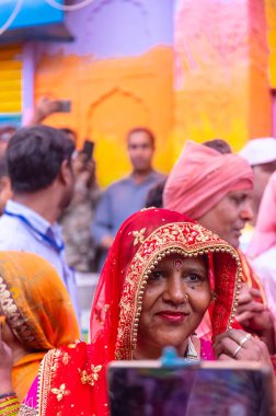 Barsana, Uttar Pradesh, India - March 18 ,2024: Group of hindu female of barsana in traditional clothes standing with bamboo sticks to hit male from nandgaon as tradition to play lathmar holi festival. clipart