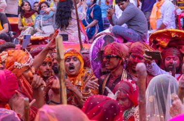 Barsana, Uttar Pradesh, Hindistan - 18 Mart 2024: Geleneksel giysiler ve rengarenk yüzlü Hindu erkek grubu, Barsana 'nın Rangili Gali' sindeki lathmar Holi 'yi geleneksel olarak kutluyorlar..