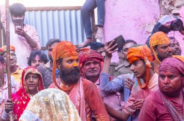 Barsana, Uttar Pradesh, Hindistan - 18 Mart 2024: Geleneksel giysiler ve rengarenk yüzlü Hindu erkek grubu, Barsana 'nın Rangili Gali' sindeki lathmar Holi 'yi geleneksel olarak kutluyorlar..