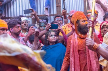 Barsana, Uttar Pradesh, Hindistan - 18 Mart 2024: Geleneksel giysiler ve rengarenk yüzlü Hindu erkek grubu, Barsana 'nın Rangili Gali' sindeki lathmar Holi 'yi geleneksel olarak kutluyorlar..