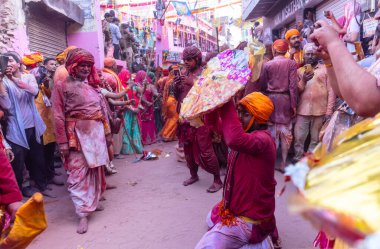 Barsana, Uttar Pradesh, Hindistan - 18 Mart 2024: Geleneksel giysiler ve rengarenk yüzlü Hindu erkek grubu, Barsana 'nın Rangili Gali' sindeki lathmar Holi 'yi geleneksel olarak kutluyorlar..