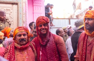 Barsana, Uttar Pradesh, India - March 18, 2024: Group of hindu male from nandgaon in traditional clothes and colorful faces celebrating the lathmar holi in rangili gali of barsana with tradition. clipart