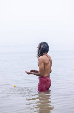 Prayagraj, Uttar Pradesh, India - January 13, 2025: Mahakumbh, Portrait of an holy male sadhu baba standing in holy river ganga to take holy dip during the shahi snaan at mahakumbh mela in prayagraj. clipart