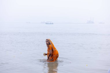 Prayagraj, Uttar Pradesh, India - January 13 2025: Mahakumbh, Portrait of an holy woman standing in holy river ganga to take holy dip during the shahi snaan at mahakumbh mela in prayagraj. clipart