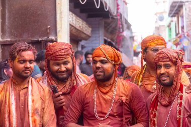 Barsana, Uttar Pradesh, India - March 18 2024: Portrait of hindu male from nandgaon protecting head with leather shield from a bamboo stick hitting by a women of barsana as a tradition of lathmar holi clipart