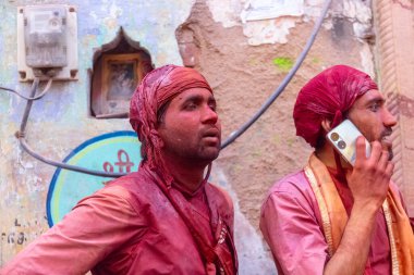 Barsana, Uttar Pradesh, India - March 18 2024: Portrait of hindu male from nandgaon protecting head with leather shield from a bamboo stick hitting by a women of barsana as a tradition of lathmar holi clipart