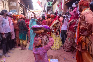 Barsana, Uttar Pradesh, Hindistan - 18 Mart 2024: Nandgaon 'dan Hindu erkek portresi Kafasını deri bir kalkanla koruyor Barsana' lı bir kadın tarafından bir lathmar holi geleneği olarak vurulan bambu çubuğu
