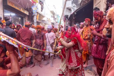 Barsana, Uttar Pradesh, Hindistan - 18 Mart 2024: Nandgaon 'dan Hindu erkek portresi Kafasını deri bir kalkanla koruyor Barsana' lı bir kadın tarafından bir lathmar holi geleneği olarak vurulan bambu çubuğu
