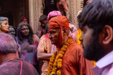 Barsana, Uttar Pradesh, India - March 18 2024: Portrait of hindu male from nandgaon protecting head with leather shield from a bamboo stick hitting by a women of barsana as a tradition of lathmar holi clipart