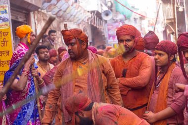 Barsana, Uttar Pradesh, Hindistan - 18 Mart 2024: Nandgaon 'dan Hindu erkek portresi Kafasını deri bir kalkanla koruyor Barsana' lı bir kadın tarafından bir lathmar holi geleneği olarak vurulan bambu çubuğu