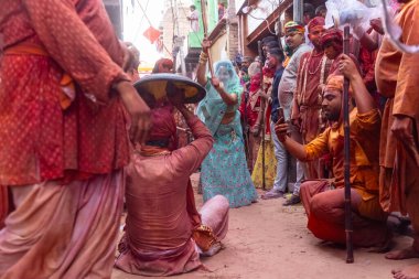 Barsana, Uttar Pradesh, Hindistan - 18 Mart 2024: Nandgaon 'dan Hindu erkek portresi Kafasını deri bir kalkanla koruyor Barsana' lı bir kadın tarafından bir lathmar holi geleneği olarak vurulan bambu çubuğu