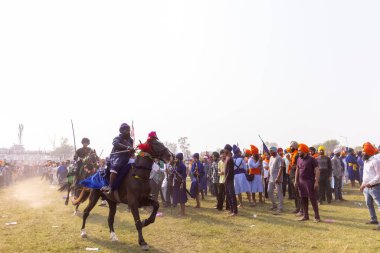 Anandpur Sahib, Punjab, India - March 19 2022: Portrait of sikh male (Nihang Sardar) performing martial art and polo while riding on horse during the hola mohalla festival during holi in punjab. clipart