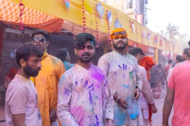 Barsana, Uttar Pradesh, Hindistan - 18 Mart 2024: Geleneksel giysiler ve rengarenk yüzlü Hindu erkek grubu, Barsana 'nın Rangili Gali' sindeki lathmar Holi 'yi geleneksel olarak kutluyorlar..