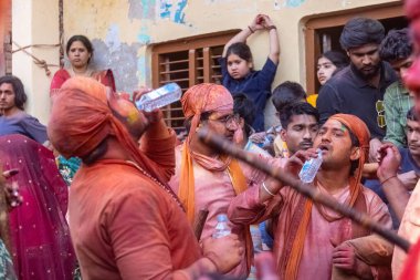 Barsana, Uttar Pradesh, Hindistan - 18 Mart 2024: Geleneksel giysiler ve rengarenk yüzlü Hindu erkek grubu, Barsana 'nın Rangili Gali' sindeki lathmar Holi 'yi geleneksel olarak kutluyorlar..