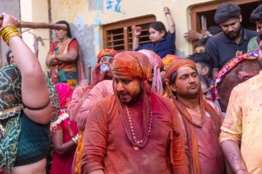 Barsana, Uttar Pradesh, Hindistan - 18 Mart 2024: Geleneksel giysiler ve rengarenk yüzlü Hindu erkek grubu, Barsana 'nın Rangili Gali' sindeki lathmar Holi 'yi geleneksel olarak kutluyorlar..
