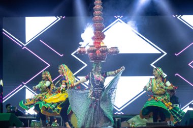 Bikaner, Rajasthan, Hindistan - 14 Ocak 2023: Güzel Hintli kadın sanatçı, geleneksel kıyafetlerle bikaner deve festivali sırasında kafasında çamur tencereleriyle geleneksel halk dansı yapıyor.