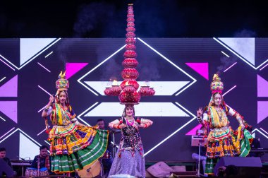 Bikaner, Rajasthan, Hindistan - 14 Ocak 2023: Güzel Hintli kadın sanatçı, geleneksel kıyafetlerle bikaner deve festivali sırasında kafasında çamur tencereleriyle geleneksel halk dansı yapıyor.